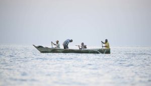 Local fishermen working their nets from a canoe on Lake Victoria