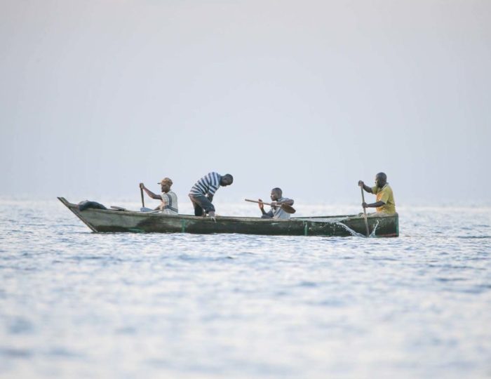 Local fishermen working their nets from a canoe on Lake Victoria