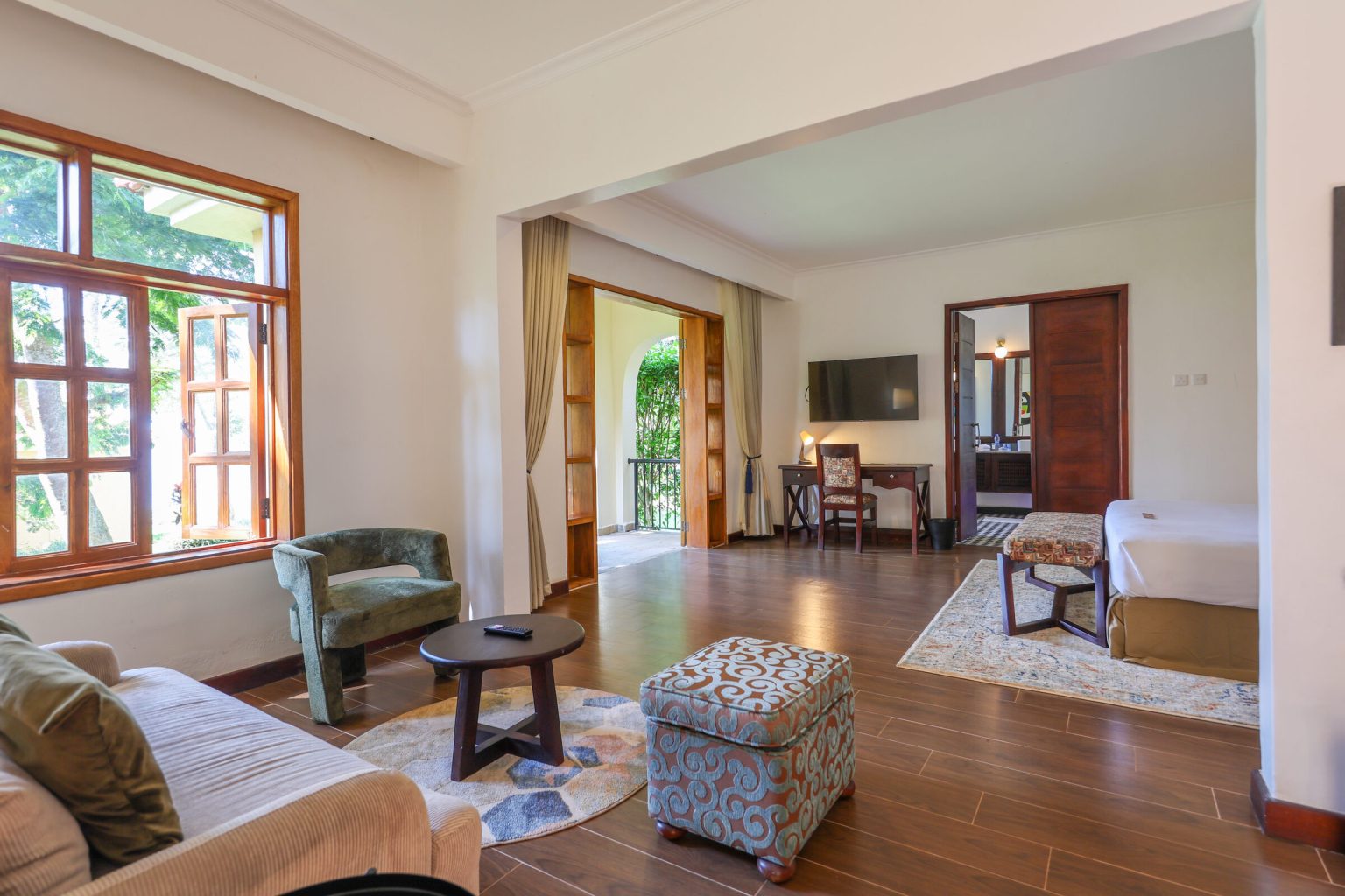 A large suite looking from the lounge through to a desk, television and bedroom beyond.